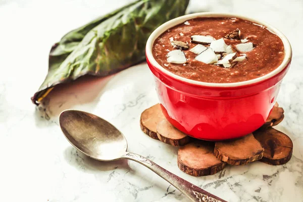 Budín de chocolate en un tazón rojo, con coco, bayas y chía —  Fotos de Stock