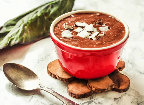 Chocolade pudding in een rode kom, met bessen, kokos en chia s — Stockfoto