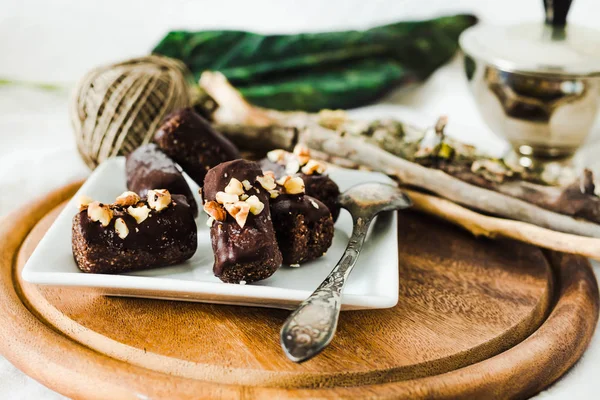 Dulces de chocolate crudo saludable con nueces en un pla cuadrado blanco — Foto de Stock