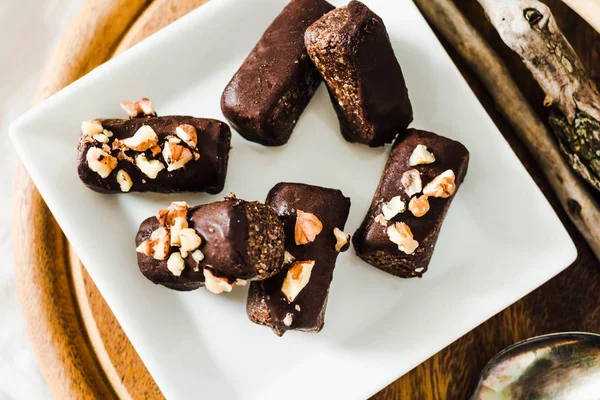 healthy raw chocolate candies with walnuts on a white square pla