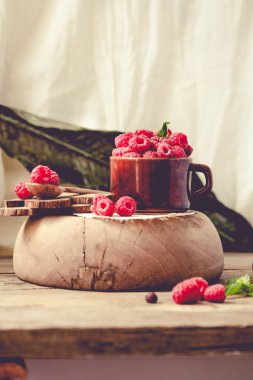 Bir fincan kahve ve bir ahşap stand Fesleğenli taze ahududu