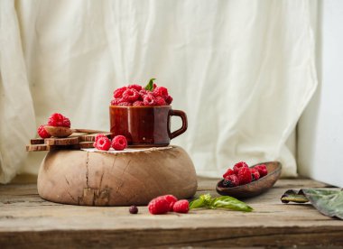 Bir fincan kahve ve bir ahşap stand Fesleğenli taze ahududu