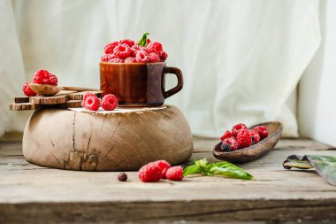 Bir fincan kahve ve bir ahşap stand Fesleğenli taze ahududu