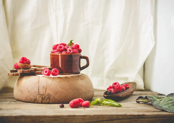 Frambuesa fresca con albahaca en una taza de café y un soporte de madera — Foto de Stock