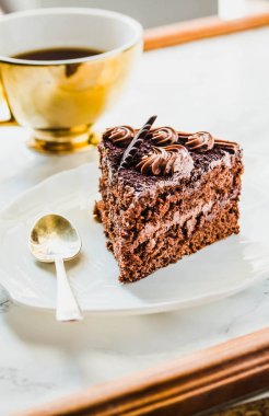 Beyaz tabakta çikolatalı pasta ve sarı çay fincanı. Sele