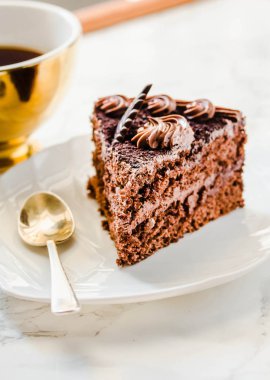 Beyaz tabakta çikolatalı pasta ve sarı çay fincanı. Sele
