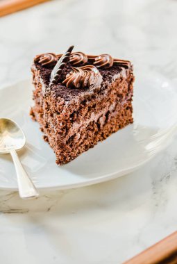 Beyaz tabakta çikolatalı pasta ve sarı çay fincanı. Sele