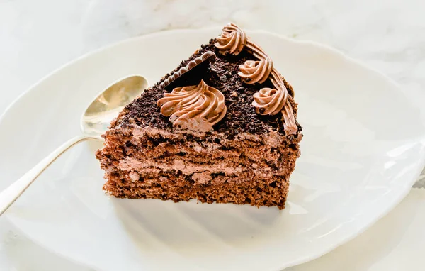 Pastel de chocolate en un plato blanco y una taza de té de oro amarillo. Sele. — Foto de Stock