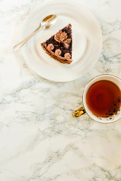 Tallrik med skiva av hemlagad chokladkaka och gul guldkopp — Stockfoto