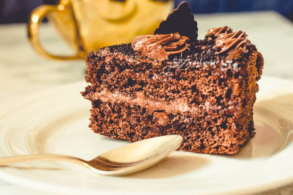 Un pedazo de pastel de chocolate en un plato blanco y una taza de café de oro , — Foto de Stock