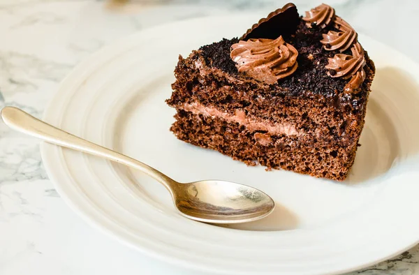 Un pedazo de pastel de chocolate en un plato blanco y una taza de café de oro , — Foto de Stock