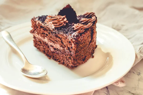 Beyaz tabakta bir parça çikolatalı kek ve bir fincan altın kahve., — Stok fotoğraf