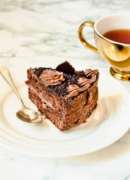 Un pedazo de pastel de chocolate en un plato blanco y una taza de café de oro , — Foto de Stock