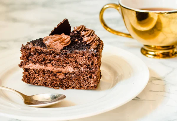 Un pedazo de pastel de chocolate en un plato blanco y una taza de café de oro , — Foto de Stock