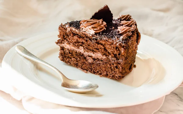 Kawałek ciasta czekoladowego w białym talerzu i złota filiżanka kawy, — Zdjęcie stockowe
