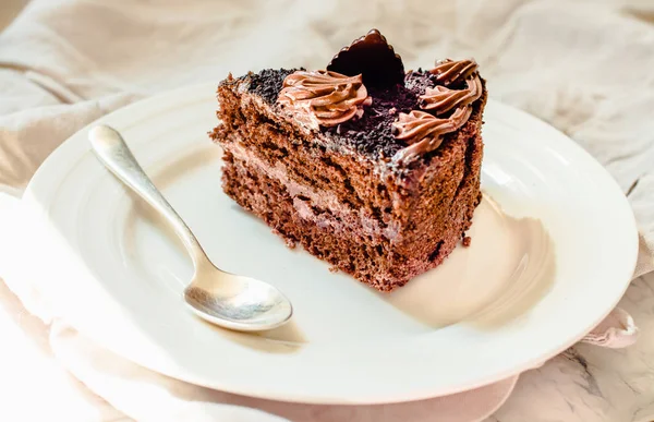 Un pedazo de pastel de chocolate en un plato blanco y una taza de café de oro , — Foto de Stock