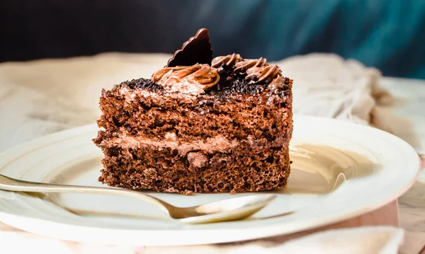 Una rebanada de delicioso pastel de chocolate en un mantel de lino blanco . — Foto de Stock
