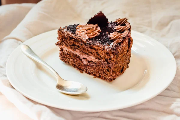 Une tranche de délicieux gâteau au chocolat sur une nappe en lin blanc . — Photo