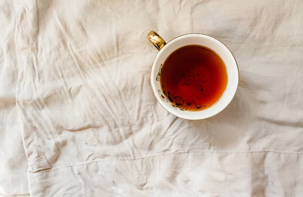 Gelbgold Tasse Tee auf weißem Leinentischtuch. Ansicht von oben. kinf — Stockfoto