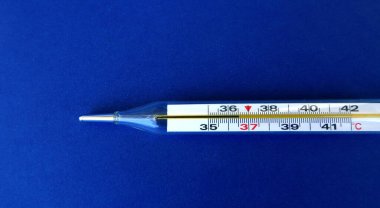                          İlaç hapları, beyaz şişe, termometre ve maske mavi arka planda.              