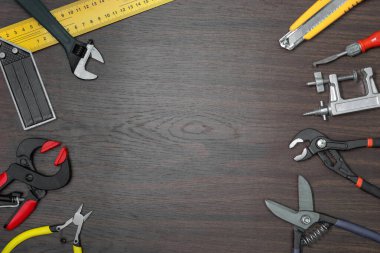 Koyu kahverengi ahşap masa üzerinde farklı tamir araçları bulunur.