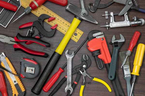 Different used tools lie on wooden background in chaotic way