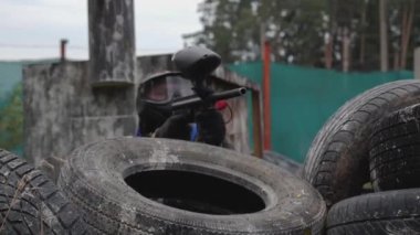 Lastiklerle çevrili bir adam paintball oynuyor.