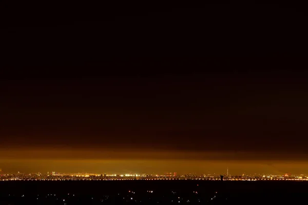 Vista dalla collina su una snella città di notte ai piedi — Foto Stock