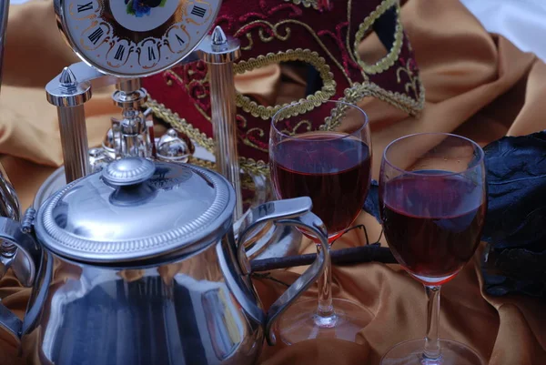 Karanlık, gizemli bir kompozisyonda bir bardak şarap ve maske