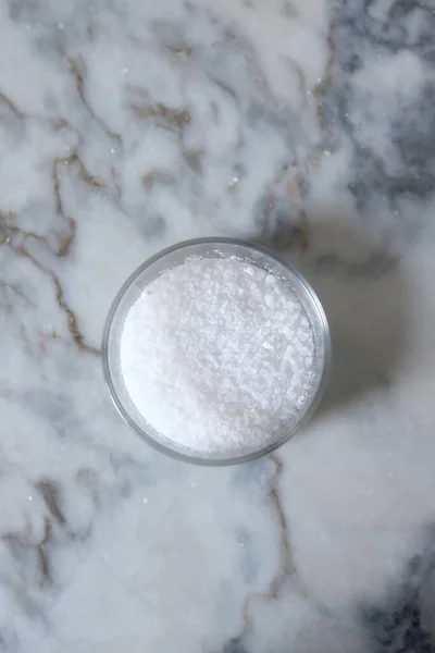 En üstten mermer tezgah manzaralı cam bir tencerede deniz tuzu.