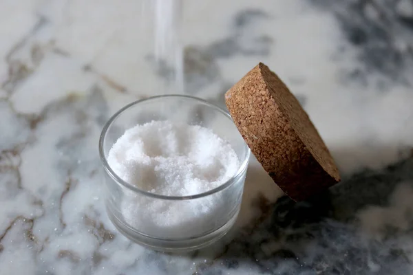 Doğal ışık altında mermer tezgahın üzerinde cam bir tencerede deniz tuzu.