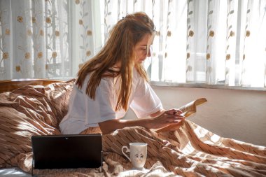 Yataktaki genç bayan, sabahın ilk ışıklarına evde çalışarak hoş geldin.