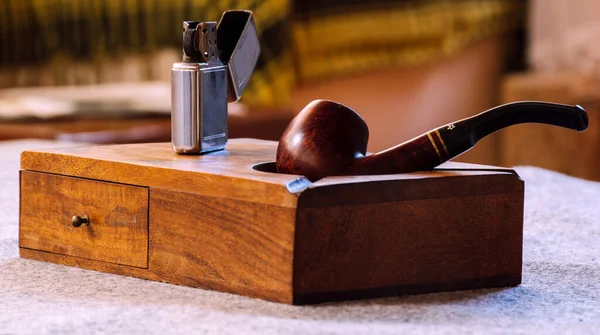 Özel sigara seti, ahşap kutunun üzerinde ahşap pipo ve klasik benzin çakmağı.