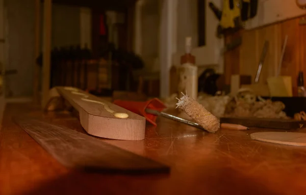 Atölyedeki gül ağacından fretboard montajı sırasında müzik aletinin boynuna akan parlak sarı ahşap yapıştırıcı - atölyede sabahın erken saatlerinde yakın çekim sahnesi
