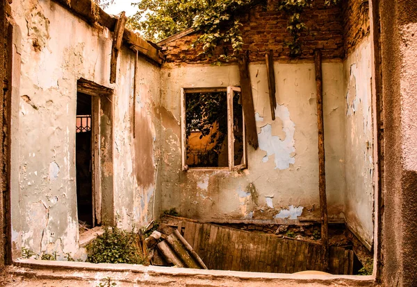 Terk edilmiş eski bir yıkık dökük evin içinde, yaşanmaz durumda, zemin çökmüş, bütün boyalar duvarlardan soyulmuş ve ahşap çerçeveler.