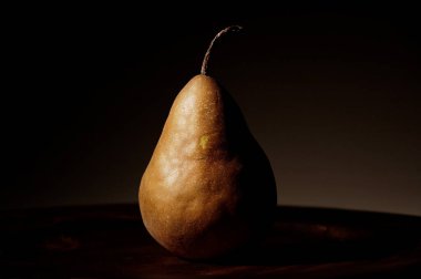 Kahverengi zemin üzerinde taze tek bir armut.