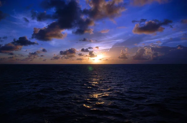 Ein Sonnenuntergang über einem Gewässer mit klarem Ozeanhimmel — Stockfoto