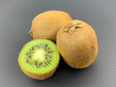 Mavi arka planda taze olgun ve yarım kivi meyvesi. Düz konum, kare biçimi