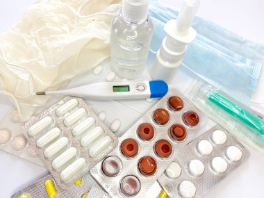 Farklı ilaçlar: tabletler, su toplayan haplar, ilaçlar ilaçlar, tıbbi eldivenler, maske, şırınga, termometre, sprey, beyaz arka planda dezenfektan. Yatay fotoğraf