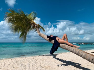 Bikini ve mavi pareolu güneş gözlüklü güzel, mutlu, Avrupalı kız Dominik Cumhuriyeti 'nin Saona adasındaki beyaz kumsalda hindistan cevizi palmiyesinde yatıyor. Tatil resmi