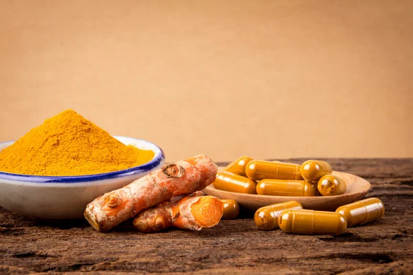 Kurkuma-Pulver, Kapsel und Curcumin-Wurzeln auf Holzteller — Stockfoto