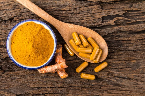 Kurkuma-Pulver, Kapsel und Curcumin-Wurzeln auf Holzteller — Stockfoto