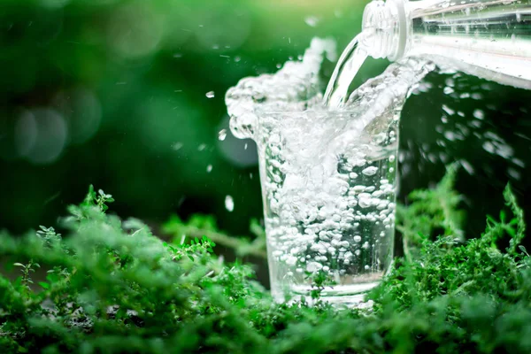Sklenici chladné pitné vody na přírodní zelené pozadí — Stock fotografie