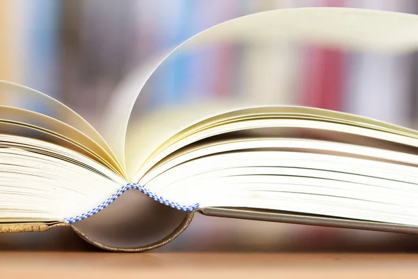 Tutup halaman buku yang dibuka dengan latar belakang rak buku yang kabur — Stok Foto