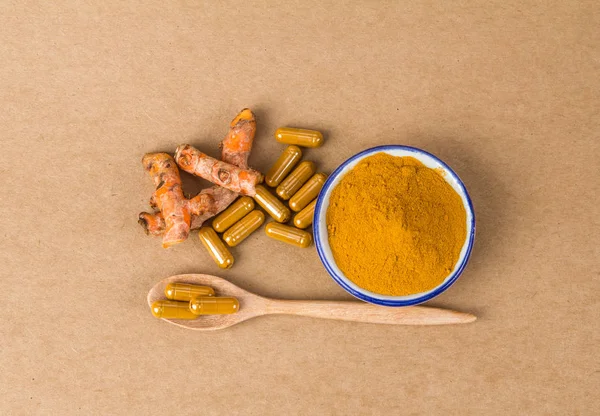 the turmeric powder and capsule and roots curcumin on brown pape