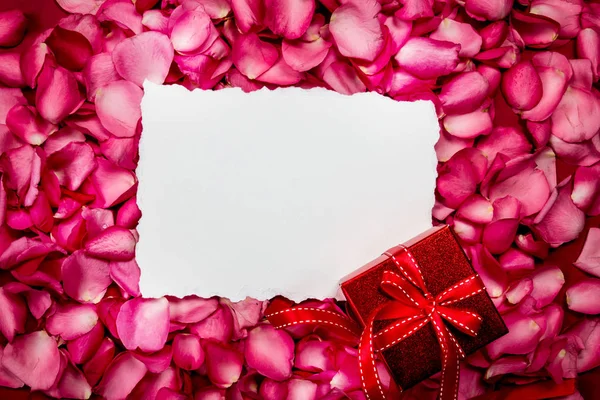 Papier vide avec pétales de roses roses douces et boîte cadeau rouge — Photo