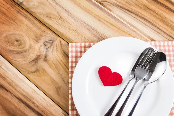 red heart shape with White empty plate with fork and spoon