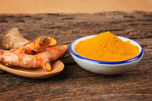 Kurkuma-Pulver und Curcumin-Wurzeln auf Holzteller — Stockfoto