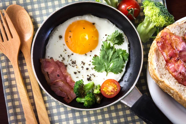 煎的鸡蛋和培根在黑暗泛在桌子上一起吃早餐 — 图库照片