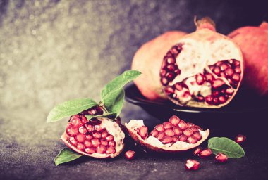 Taze kırmızı nar ve tohum yaprakları üzerinde siyah taş ile